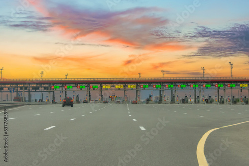 View gate for cars at the entrance to the toll road, limited by the barrier sunset evening view. Cashless payment transponder, speed limit signs.