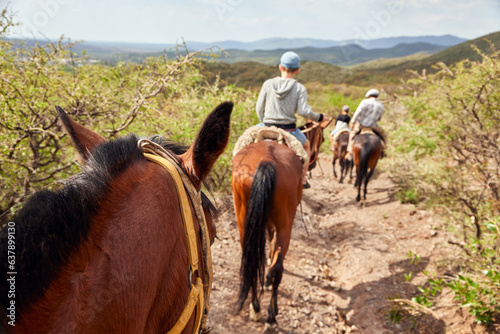 Family riding on horseback through the hills guided by an Argentine gaucho.