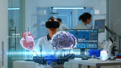 Scientific expert in modern lab wearing VR headset, using advanced equipment and wired sensors to contribute to neurology research. Specialist using virtual reality technology to gain medical insights
