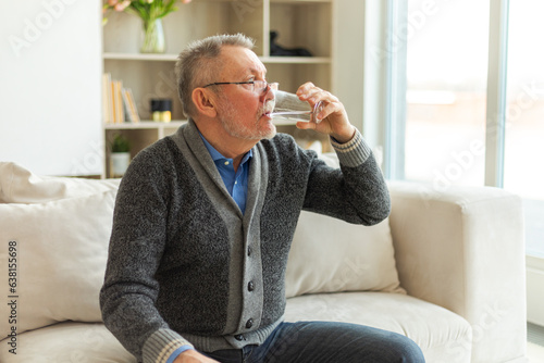 Senior man holding glass drinking fresh water at home. Mature old senior thirsty grandfather takes care of his health. Healthcare water balance. Elderly healthy lifestyle