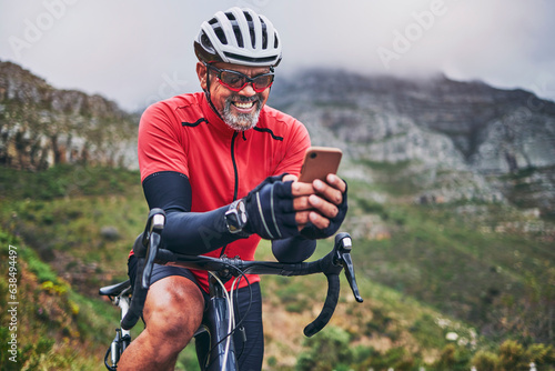 Happy man, cyclist and phone on mountain bicycle in communication, social media or networking in nature. Male person or athlete smile on mobile smartphone app in sports workout, fitness or cycling