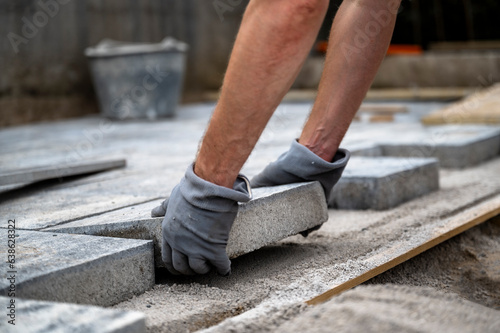 DIY project - male hands paving outdoor patio with cement tiles