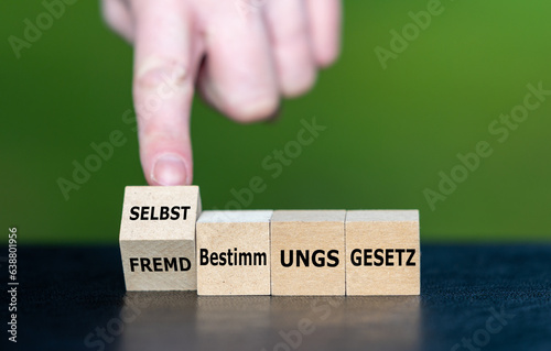 Hand dreht Holzwürfel und ändert den Ausdruck Fremdbestimmungsgesetz in Selbstbestimmungsgesetz.