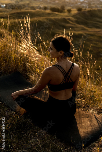 Woman doing yoga under a tree at sunset.The concept of yoga 