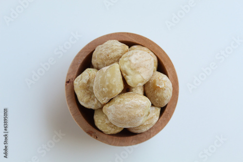 Dried Indonesian Candlenuts, or Kemiri, the seed of Aleurites moluccanus inside a wooden bowl, isolated in white background. Flat lay or top view