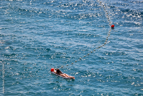 Młoda dziewczyna w stringach płynie na materacu po morzu. 