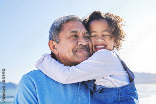 Grandfather, child and happy at the beach for vacation and travel together on outdoor holiday for happiness. Hug, smile and grandparent with kid or young grandchild by the ocean or sea for adventure