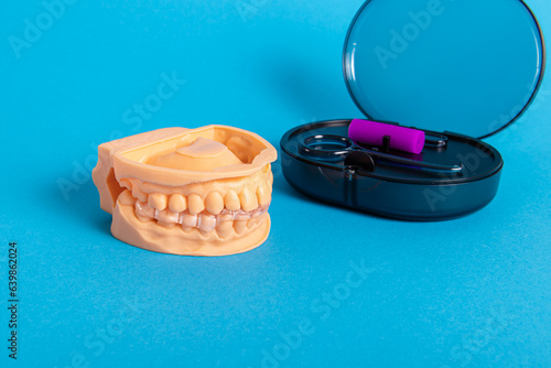 Transparent invisible aligners for teeth and set for the care of aligners on blue background. Jaw model and case