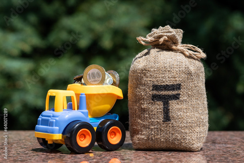 Money bag and toy dump truck with 100 Kazakhstani tenge coins