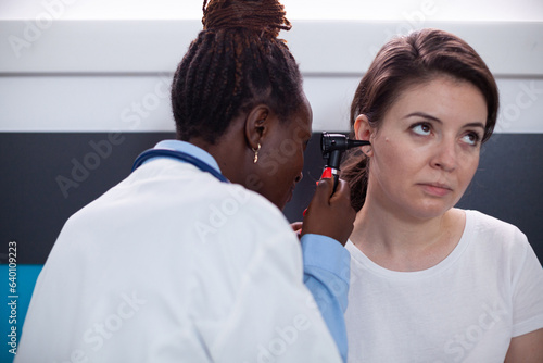 Otology specialist doctor checking for patient earache, ruptured eardrum, tinnitus and deafness ear symptoms. Medic using otolaryngology instrument in clinic office during medical appointment