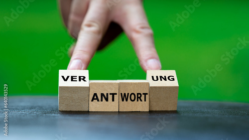 Hand dreht Holzwürfel und ändert das Wort 'Antwort' in 'Verantwortung'. Symbol dafür Verantwortung zu übernehmen.