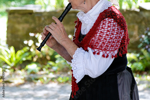 Senior woman playing the recorder in traditional clothes