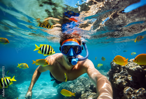 Man snorkeling in the tropical water with colorful fishes and corals. Shallow field of view