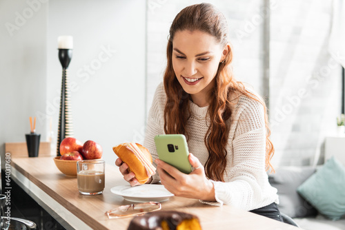 Young woman eats bread and drinks latte at home