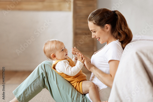 Loving young mother caressing her cute baby boy, home interior