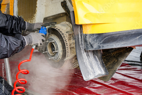 Rally car maintenance in service park, blowing off dust from the brake disc with compressed air