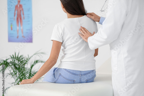 Male doctor checking posture of young woman in clinic