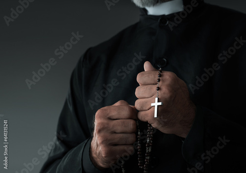 Close up of a priest holding rosary with copy space