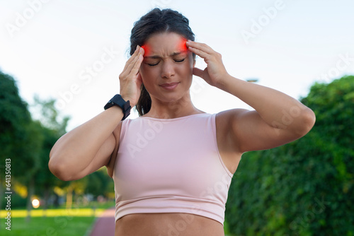 Sportwoman suffering severe headache with suffering and painful expression