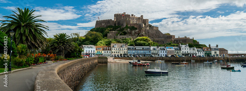 Panoramic image of Mont Orgueil Castle in Gorey on the island of Jersey in the Channel Islands. Fishing boats and colourful buildings with sunshine and blue sky