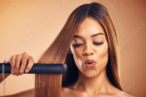 Excited, hair straightener and a woman in studio for beauty, cosmetics or appliance. Aesthetic model on brown background for wow heat treatment, healthy results and hairdresser or salon flat iron