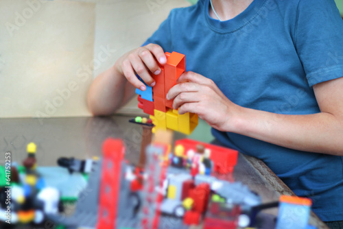 An unrecognizable boy assembles multi-colored constructor.