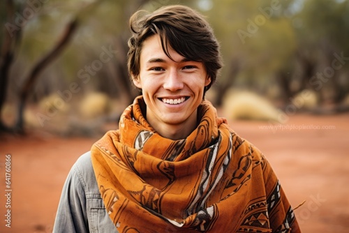 Environmental portrait photography of a happy boy in his 20s wearing an elegant silk scarf near the uluru (ayers rock) in northern territory australia. With generative AI technology