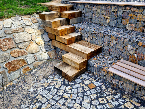 how to solve the steep entrance to the water on the dam. oak beams stacked and screwed together in a chaotic direction on top of each other. gabion slope go down the stairs