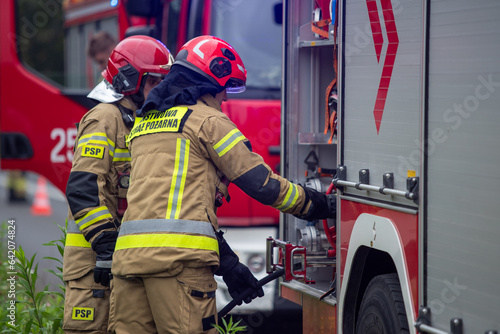 Strażacy podłączający wąż. Straż pożarna przy wypadku. Strażacy gaszą samochód. Straż pożarna gasi płonący samochód. Firemen connecting a hose. The fire department at the accident. Firefighters exting