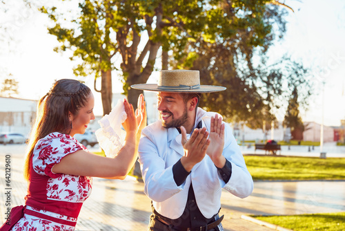 retrato pareja joven vestidos con ropa tradicional huaso aplaudiendo al ritmo del baile de cueca en la plaza