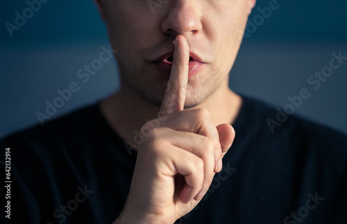 Secret and silence. Quiet silent shh gesture with finger on lips. Man doing expression with hand on mouth. Taboo topic, censorship or freedom or speech. Conspiracy theory. Confidential talk.