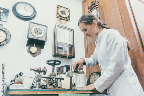 Woman watchmaker cleaning clockwork of a watch in her workshop