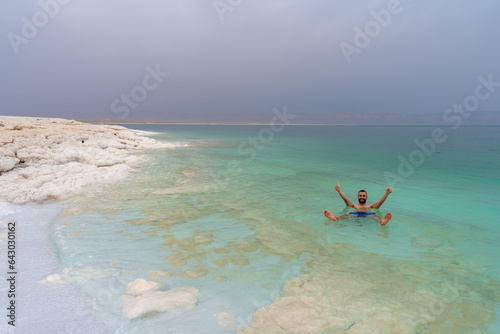 Happy tourist man taking a bath and floating in the Death Sea, Jordan