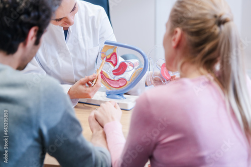 Couple wishing to have children in fertility clinic with doctor looking happy upon good news