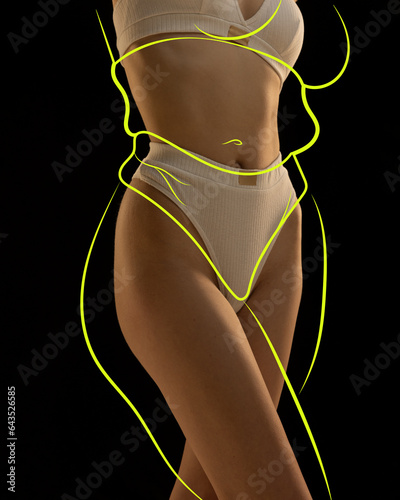Cropped slim female body in khaki lingerie with drawn yellow silhouette around body posing against black background. body positivity