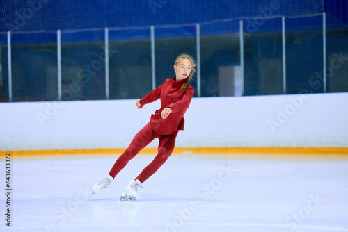 Concentrated and motivated teen girl in red sportswear training, skating on ice rink arena. Figure skating athlete. Concept of professional sport, competition, sport school, health, hobby, ad