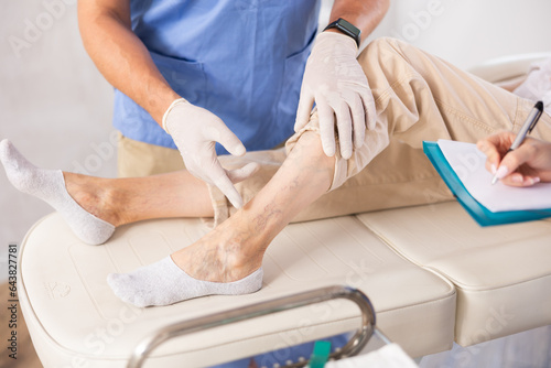 Professional phlebologists carefully examining legs with signs of varicose veins of female patient lying on couch in clinic, cropped shot..