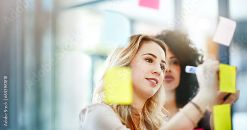 Business women, team writing and glass board for startup planning, marketing project and scrum or agile sticky notes. Young creative employees with ideas and vision, goals or brainstorming on window