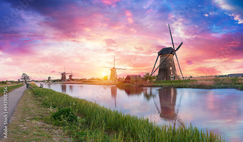 Landscape with tulips, traditional dutch windmills and houses near the canal in Zaanse Schans, Netherlands, Europe. High quality photo