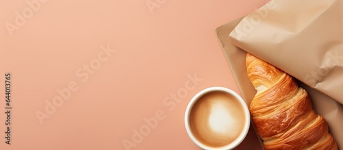 Croissant in paper with coffee Breakfast or snack isolated pastel background Copy space