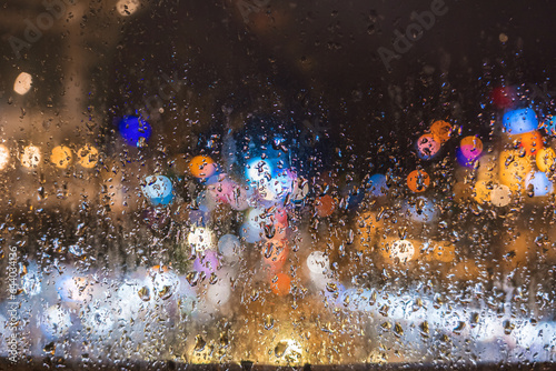 City view through the window on a rainy night, Rain falling on the window with light effect