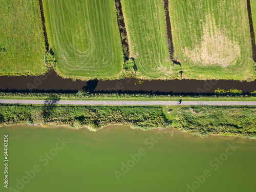 aerial shot of land and water, recreation meets faming at the surfplas manmade lake in Reeuwijkse plassen. Cycle path separates wetland from agricultural polders on sunny summer day