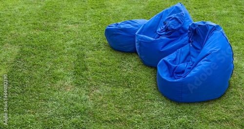Three blue bean bags on green grass
