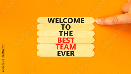 Welcome to best team symbol. Concept words Welcome to the best team ever on wooden stick on beautiful orange background. Businessman hand. Business, motivational and welcome to best team concept.
