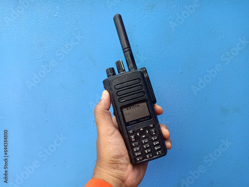 The hand of a man holding a walkie-talkie isolated on Blue color background. Mobile radio on the hand.