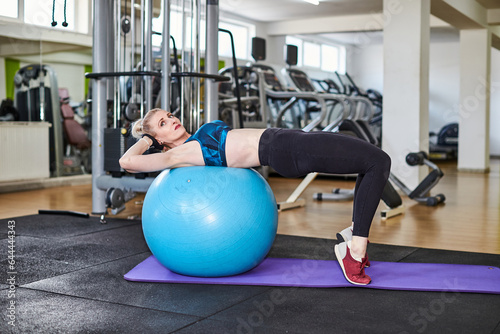 Beautiful woman is doing exercises in a fitness room with ball