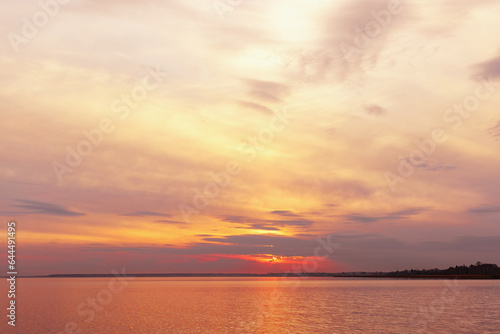 Colorful sky background on sunset, orange blue vivid color clouds and surface water on lake Ik. Nature abstract fon with reflections on water, natural shades cloudscape, nature environment