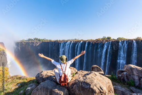 Woman sitting on the top of a rock enjoying the Victoria Falls - Zimbabwe