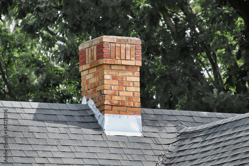 An old chimney on a shingles rooftop.