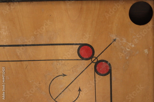 A closeup shot of an old Carrom board with scratches and focus on the hole of the carrom board 